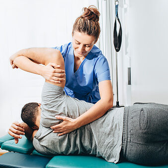 Physiotherapist treatment patient. She holding patient's hand, shoulder joint treatment